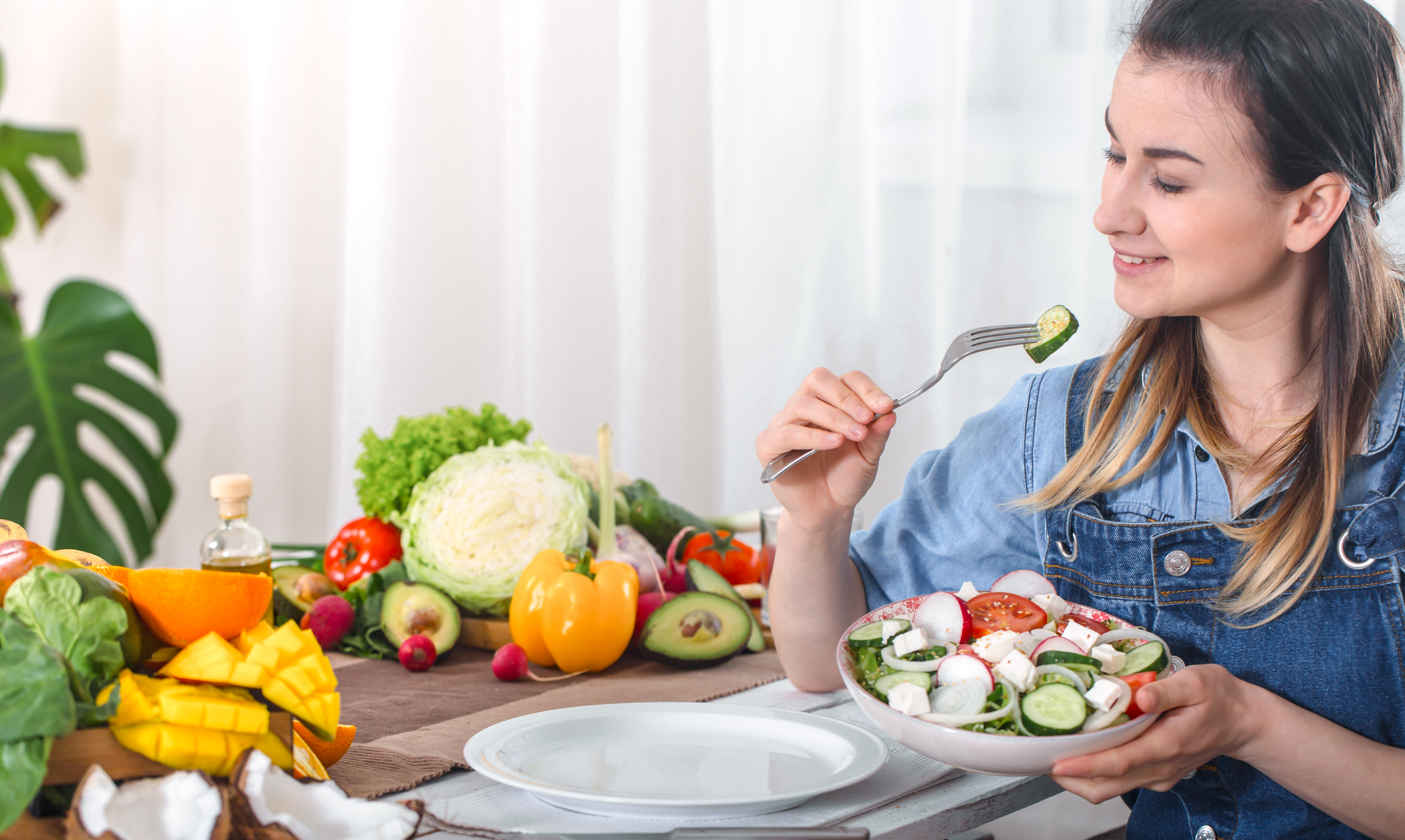 young-happy-woman-eating-salad-with-organic-vegetables-table-light-background-denim-clothes-concept-healthy-home-made-food.jpg